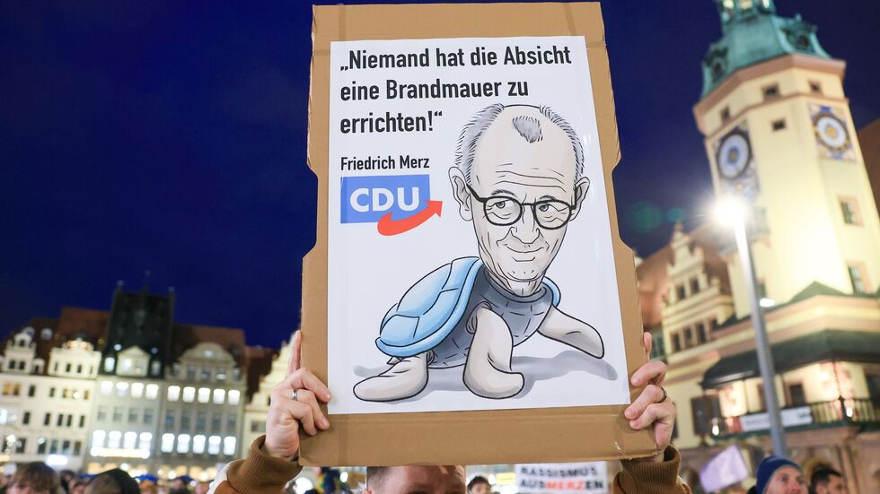Ein Demo-Teilnehmer hält ein Plakat mit der Aufschrift «Niemand hat die Absicht eine Brandmauer zu errichten» hoch.