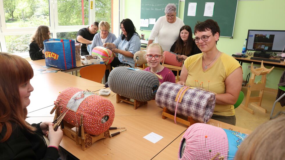 Schüler unterschiedlichen Alters klöppeln gemeinsam.