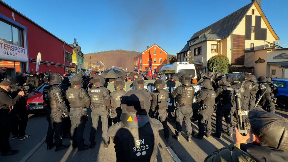 Polizisten und Demonstranten stehen sich gegenüber. Im Hintergrund ist Rauch zu sehen. Polizisten und Demonstranten stehen sich gegenüber. Im Hintergrund ist Rauch zu sehen.
