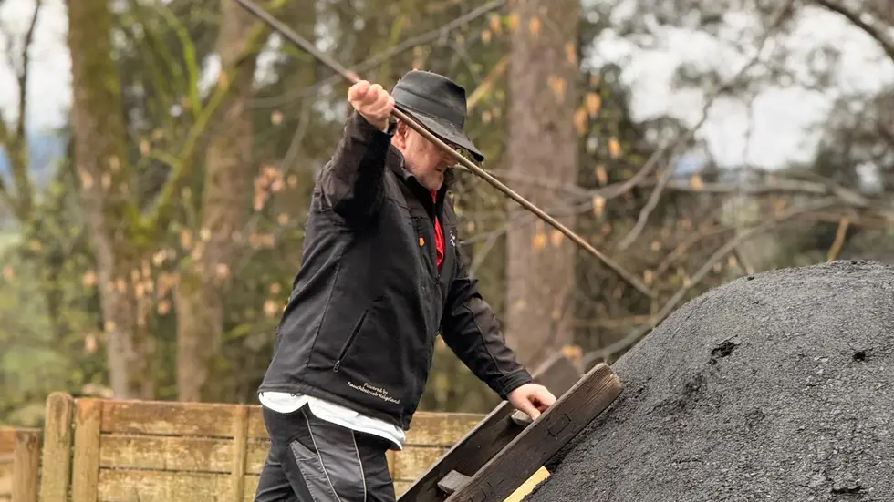 Zur Vorbereitung fürs Anzünden stach Heiko Schmidt Löcher in den Meiler.